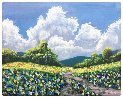 Campo de flores coloridas bajo un cielo azul con nubes esponjosas y montañas al fondo.